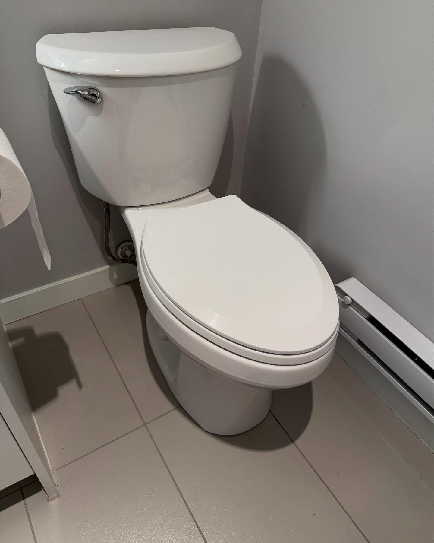 White toilet with closed lid in a bathroom with gray walls and tiled floor.