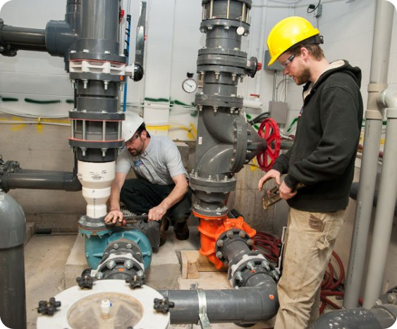 Two plumbers working on some big pipes