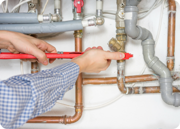 Two hands using a wrench on a pipe, close up shot